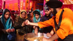 Ein Tempelanwärter verteilt heilige Gaben, Jammu, Indien