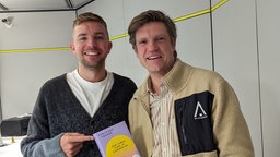 Der ehemalige Profilfußballer Christoph Kramer hält im Studio mit Moderator Thilo Jahn sein Buch "Das Leben fing im Sommer an" in der Hand.