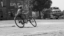 Ein Junge fährt Fahrrad ca. 1945-1955, Freiburg,  im Hintergrund zerstörte Wohnhäuser