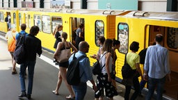 Fahrgäste steigen im U-Bahnhof am Gleisdreieck in einen U-Bahn-Wagen, während andere Fahrgäste gerade aussteigen.