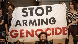 Israelische Demonstranten halten am 7. Juni 2024 in Berlin ein Transparent in die Höhe, auf dem die Worte "STOP ARMING GENOCIDE" zu lesen sind. 