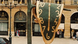 Skulptur nach Entwürfen von Dali "The Persistence of Memory": Eine große "schmelzende Uhr" hängt von einem Ast herunter.