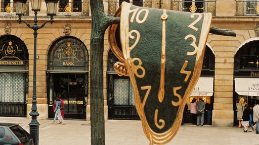 Skulptur nach Entwürfen von Dali "The Persistence of Memory": Eine große "schmelzende Uhr" hängt von einem Ast herunter.