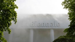 Archivaufnahme aus 2019: Ein Gebäude mit dem Schriftzug "La Biennale" in Venedig ist von weißem Nebel umgeben.