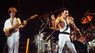 John Deacon (l) und Freddie Mercury (r), Mitglieder der britischen Rockband Queen, 1984 bei einem Auftritt in der Wembley Arena in London