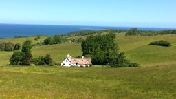 Odsherred, Dänemark. Haus in grüner Hügellandschaft, Das Meer im Hintergrund