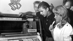 Junge Menschen stehen in einem Cafe in Helsinki an der Jukebox.