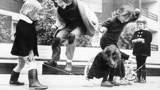 Kinder spielen Gummi hüpfen in Hof eines Wohngebietes. 