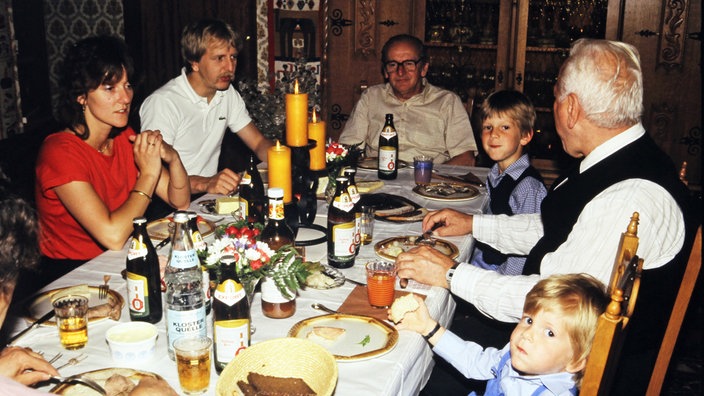 Eine Gruppe von Kindern und Erwachsenen sitzt an einem festlich geschmückten Tisch.