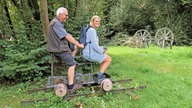 Zwei Mitglieder des Heimatvereins sitzen auf einem Grubenfahrrad.