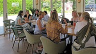 Frauen sitzen im See-Cafe und unterhalten sich. 