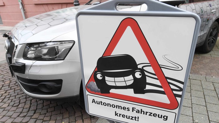 or dem Forschungsfahrzeug «Cocar» für autonomes Fahren des Forschungszentrum Informatik (FZI) in Karlsruhe (Baden-Württemberg) steht am 28.04.2016 ein Schild, auf dem «Autonomes Fahrzeug kreuzt» zu lesen ist. 