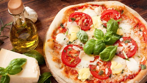 Symbolbild einer Pizza mit Tomaten, Mozarella und Basilikum.
