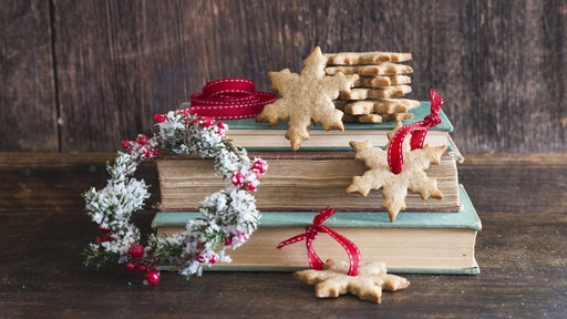 Weihnachtsplätzchen und Dekoration auf einem Stapel Bücher.