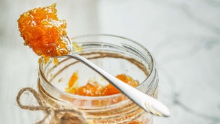 Löffel mit Orangen-Marmalade auf Einmachglas platziert. 