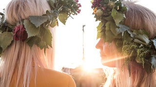 Frauen mit Blumenkränzen im Haar.