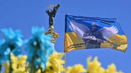 Ukrainische Flagge mit dem Porträt eines verstorbenen ukrainischen Soldaten mit Flügeln am Denkmal für gefallene ukrainische Soldaten auf dem Unabhängigkeitsplatz, Kiew, 14.08.2024.