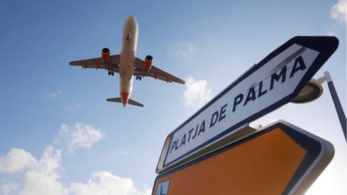 Ein Flugzeug überfliegt bei der Landung auf Mallorca ein Schild, das die Richtung nach Playa de Palma anzeigt.