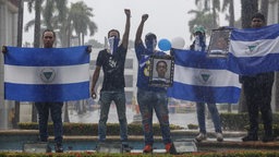 Vermummte Demonstranten halten die Fahne Nicaraguas, sowei ein Foto des getöteten Studenten Matt Romero in Managua hoch, Nicaragua, am 21 September 2019.