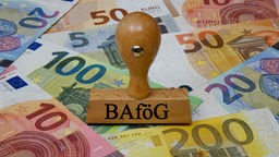 Ein Stempel mit der Aufschrift "BAföG" steht auf ausgebreiteten Gelscheinen