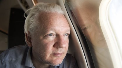 Julian Assange schaut aus dem Fenster eines Flugzeugs