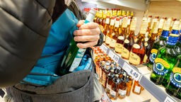 Ein Mann steckt eine Flasche Alkohol in seine Jacke.