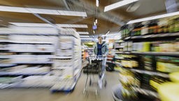 Ein Mensch mit Einkaufswagen im Supermarkt