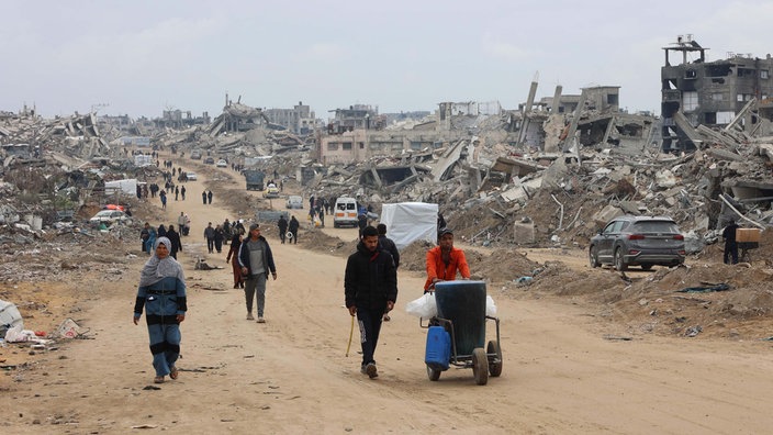 Menschen gehen im komplett zerstörten Jabalia im Norden des Gaza-Streifens eine Straße entlang.