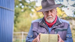 Künstler Gunter Demnig hält zwei "Stolpersteine" in seinen Händen.