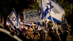 Demonstrierende tragen Israelische Flaggen und ein Plakat mit der Aufschrift "Netanjahu is a bottomless pit"