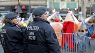 Polizisten stehen am Rande eines Karnevalsumzugs. Symbolbild: Sicherheit im Karneval