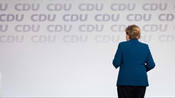 Angela Merkel verlässt eine Bühne mit CDU-Logo (2021).