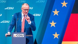 Friedrich Merz beim Wahlkampf vor CDU-Logo mit Deutschland und EU-Flagge (19.01.2025)