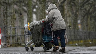 Eine obdachlose Frau schiebt ihr Hab und Gut in einem Einkaufswagen. 