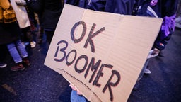 Person hält Schild mit der Aufschrift "OK, Boomer" in die Kamera