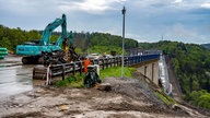 Nach der Sprengung der Rahmedetalbrücke in Lüdenscheid beginnen die Aufräumarbeiten auf der Großbaustelle. Das bis zu 70 Meter hohe und 17 000 Tonnen schwere Bauwerk war am Sonntag in ein gigantisches Fallbett gestürzt.