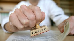 Ein Mann hält einem Stempel mit der Aufschrift "RENTE" in der Hand. Symbolbild