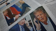 Nahaufnahmen der Cover russischer Zeitungen, die über das Telefonat zwischen Putin und Trump berichten. 