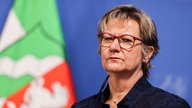 Porträtaufnahme von Sylvia Löhrmann bei einer Pressekonferenz vor einer Flagge des Landes NRW