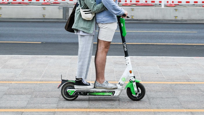 Zwei Personen fahren gemeinsam auf E-Tretroller