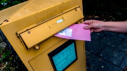 Symbolbild: Ein Briefwahlumschlag wird in einen Briefkasten geworfen.