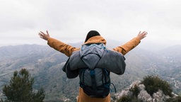 Symbolbild für Motivation: Ein Bergsteiger steht auf einem Gipfel.