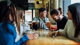 Freunde vebringen eine entspannte Zeit in einer Bar an einem Tisch.