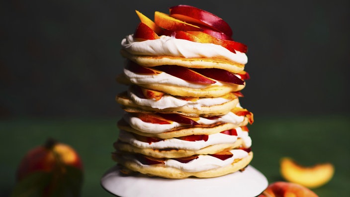 Ein Stapel Pannkuchen mit Pfirsichen dazwischen (Symbolbild, kann vom Rezept abweichen)