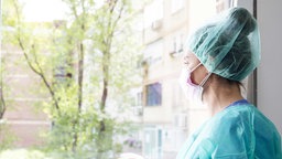 Eine Krankenpflegerin steht am Fenster