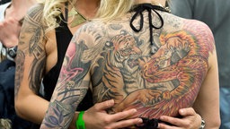 Ein Tiger und ein Drache sind am 21.03.2015 auf der "International Tattoo-Convention" in Frankfurt am Main (Hessen) auf dem Rücken einer Frau zu sehen.