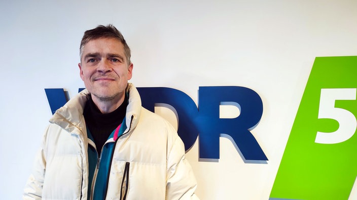 Henning Schmidtke vor dem WDR 5 Logo 