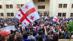 Georgien, Tiflis: Demonstranten schwenken georgische Nationalfahnen während eines Protestes der Opposition gegen das Gesetz über ausländische Einflussnahme vor dem Parlamentsgebäude.