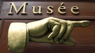 Symboldbild: Eine große goldene Hand in Paris weist den Weg zum Museum, darüber in goldener Schrift "Musée".