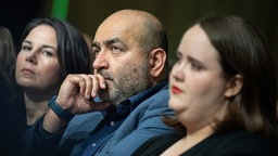 Annalena Baerbock, Omid Nouripour und Ricarda Lang (v.l.n.r.) hören nachdenklich einer Rede zu. 